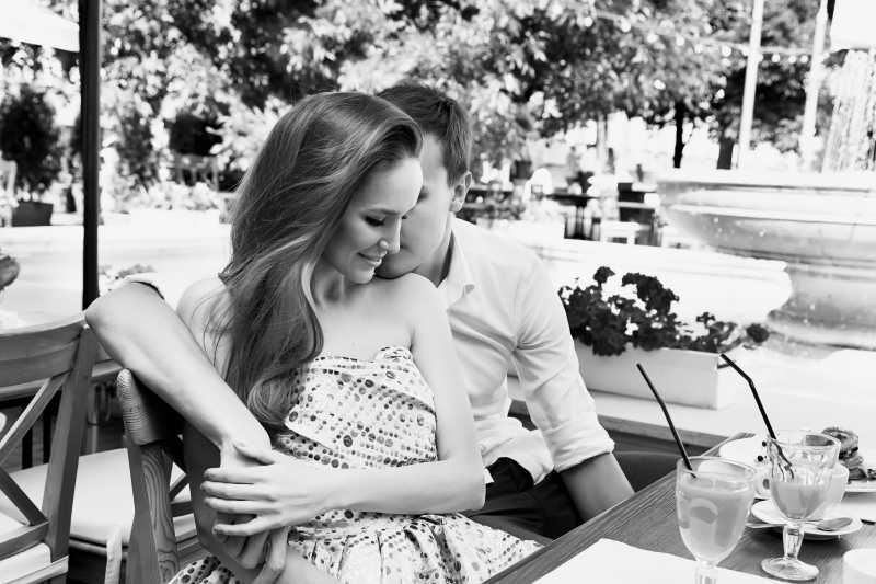 在户外餐厅亲密耳语的情侣