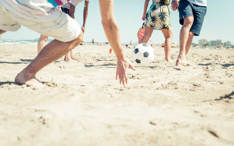 在踢海滩足球的年轻人