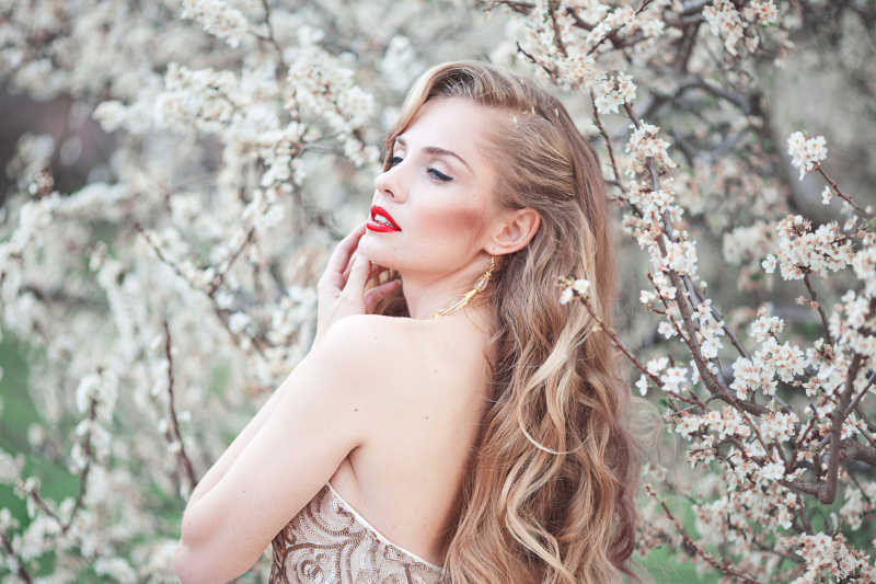 公园里桃花旁年轻漂亮的金发女郎