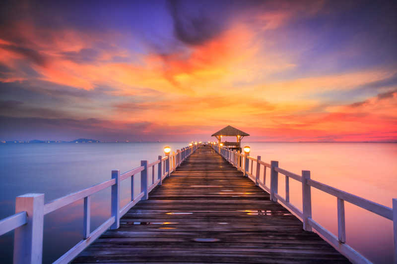 夕阳背景下的湖面上的木制桥