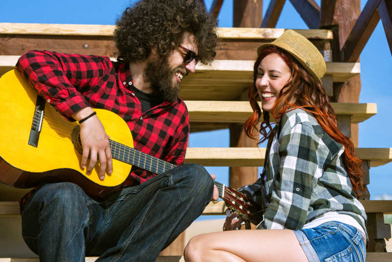 户外台阶上弹吉他的年轻夫妇