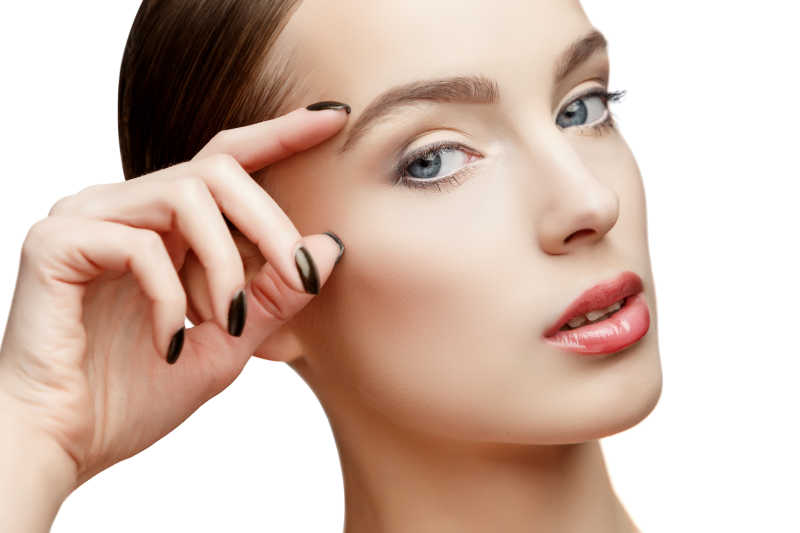 白色背景下年轻女人对于眼部皮肤的护理