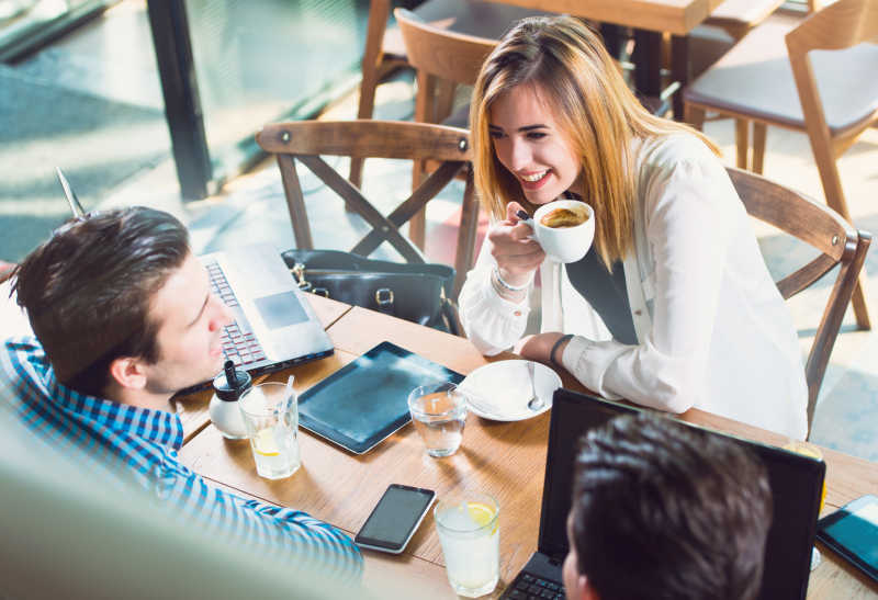 在桌旁边喝咖啡边聊天的年轻人