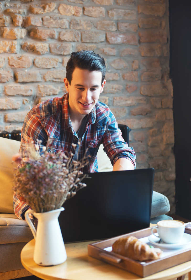 年轻人坐在咖啡馆里用笔记本电脑