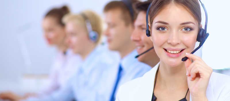 呼叫中心里戴着耳麦的年轻女客服和同事