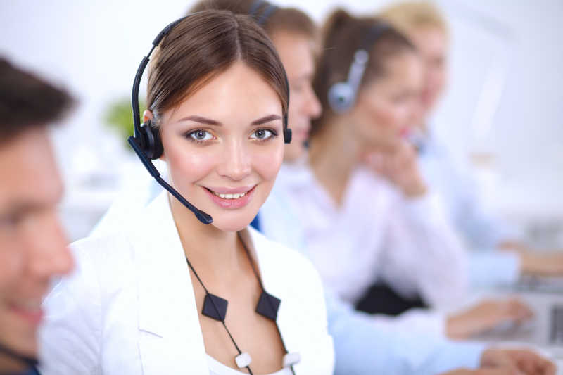 呼叫中心办公室里戴着耳麦的女客服和同事