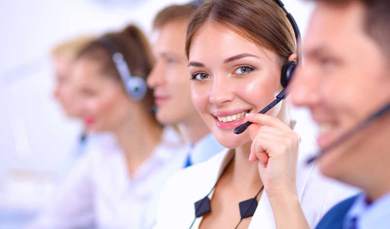 呼叫中心里戴着耳麦微笑的女客服和同事