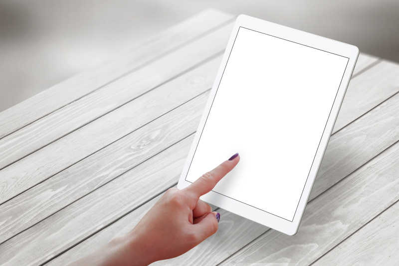 女孩用手指点击着桌子上的平板电脑屏幕