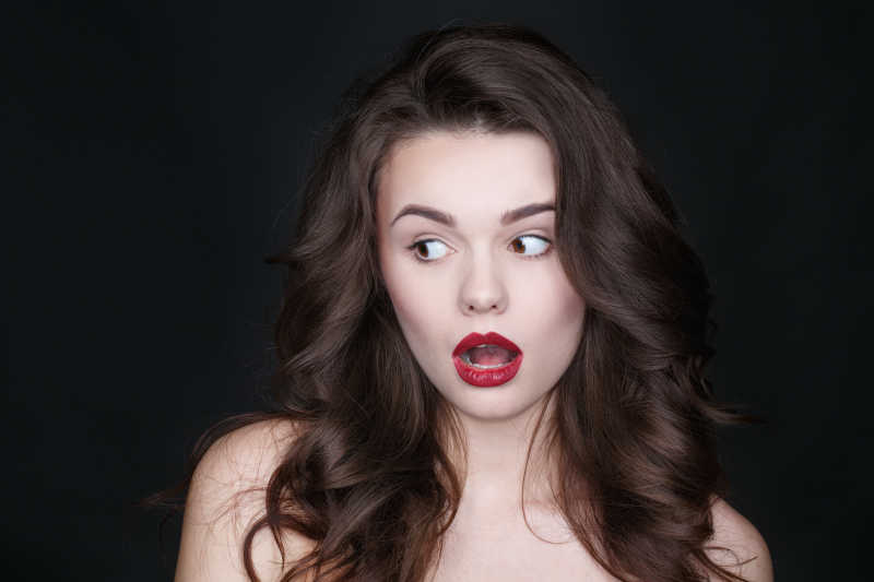 黑色背景下露出震惊表情的年轻美女