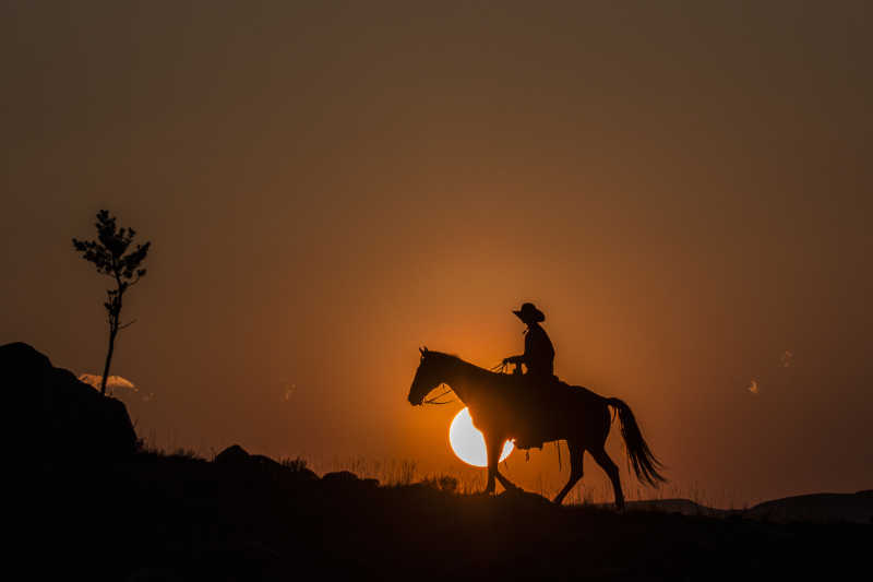 夕阳下骑马的牛仔