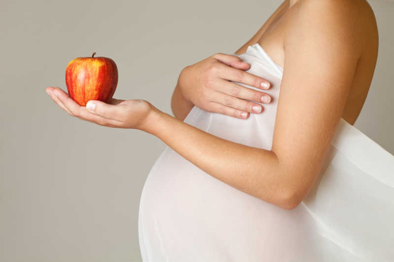 孕妇穿拿着红苹果