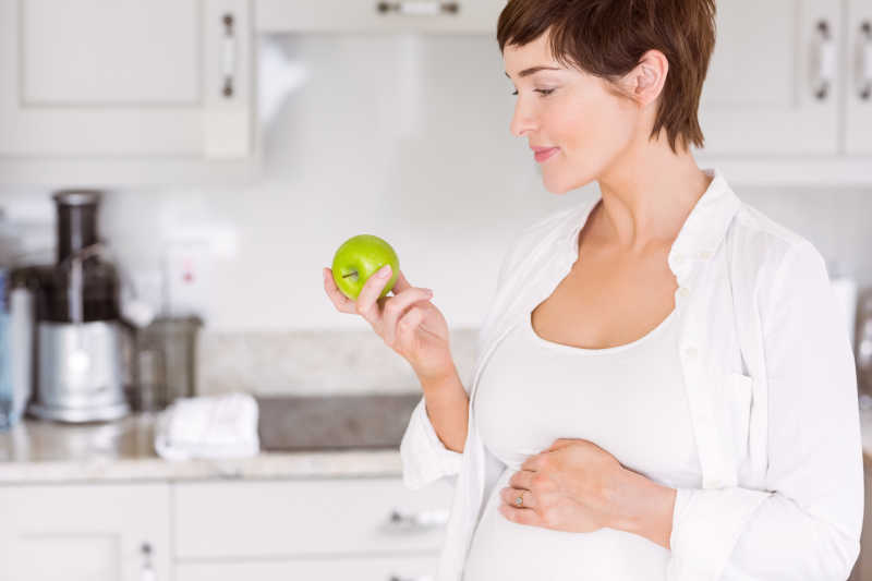 孕妇在家里在厨房里吃苹果