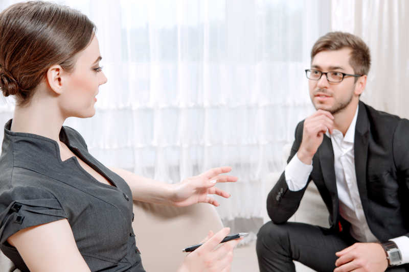 年轻人身穿黑色西装坐在沙发上看医生