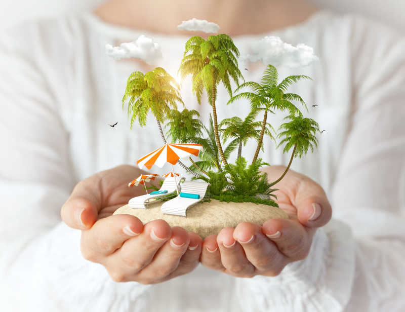 女人手捧着有棕榈树和沙滩椅的小岛