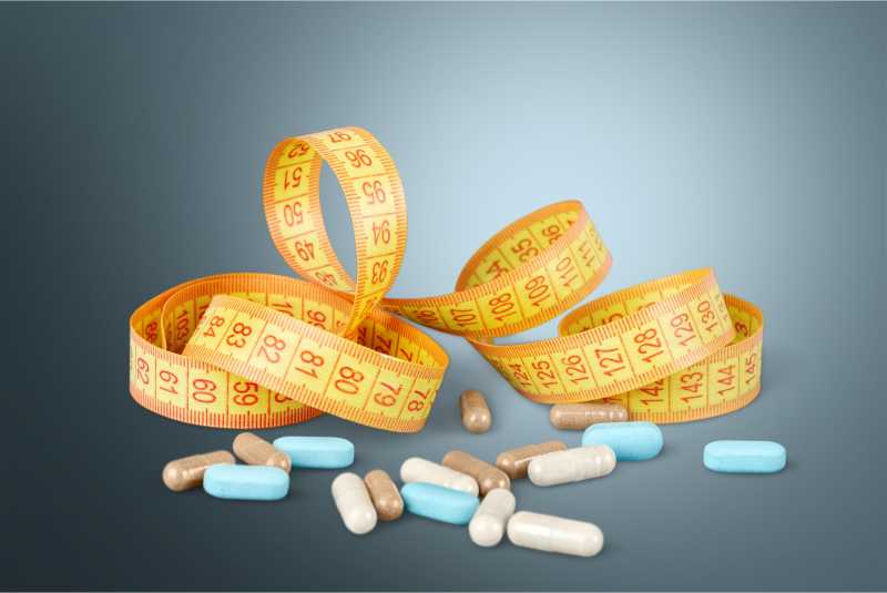 灰色背景下的药片与卷尺