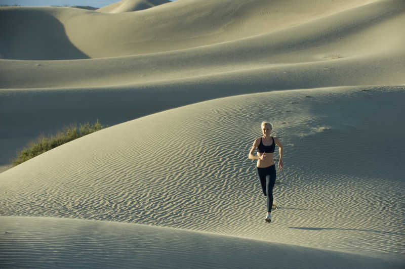阳光下在沙漠中向前奔跑的女子