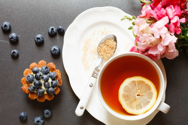 黑色餐桌上的柠檬茶与蓝莓蛋糕