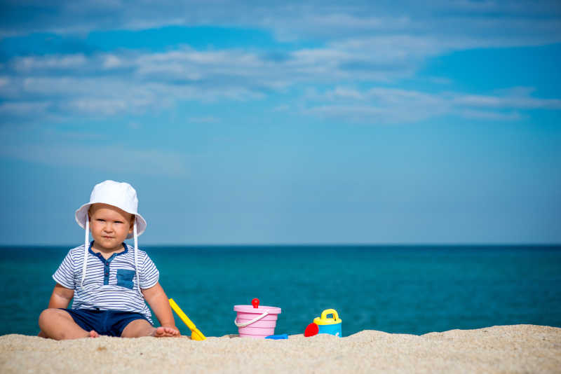 一个人坐在海滩上的小男孩