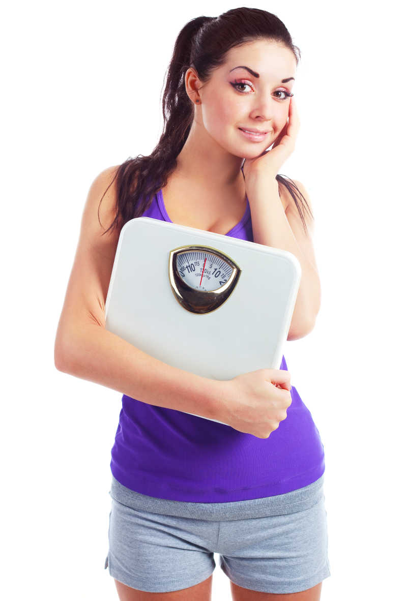 白色背景下年轻漂亮的黑发女子拿着秤