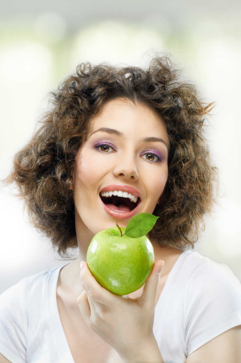 美女拿着青苹果对着镜头微笑