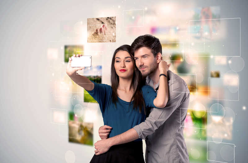 幸福的年轻夫妇以照片为背景在自拍