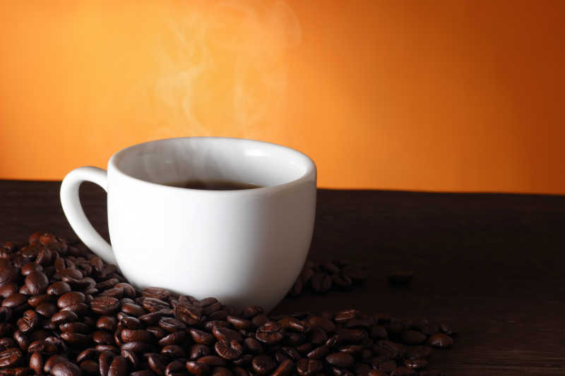 橘黄色背景上的咖啡与咖啡豆