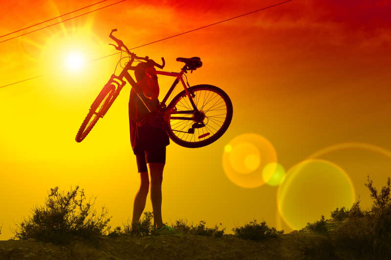 夕阳下举着自行车的帅气男孩