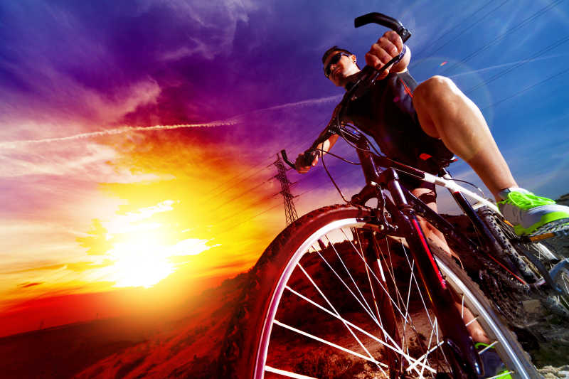 夕阳下骑着山地自行车的健硕青年