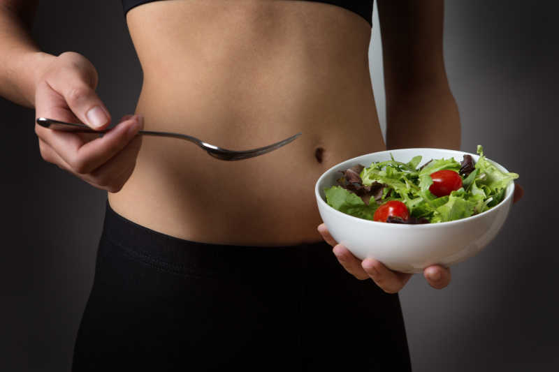 年轻的女孩手里拿着一碗沙拉