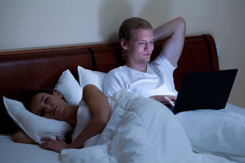 晚上仍在玩电脑的丈夫和已经熟睡的妻子