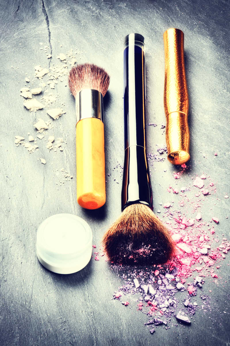 深色背景下化妆刷和压碎的眼影