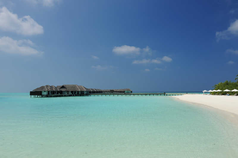 蓝天白云背景下清澈海面上的黑色度假屋