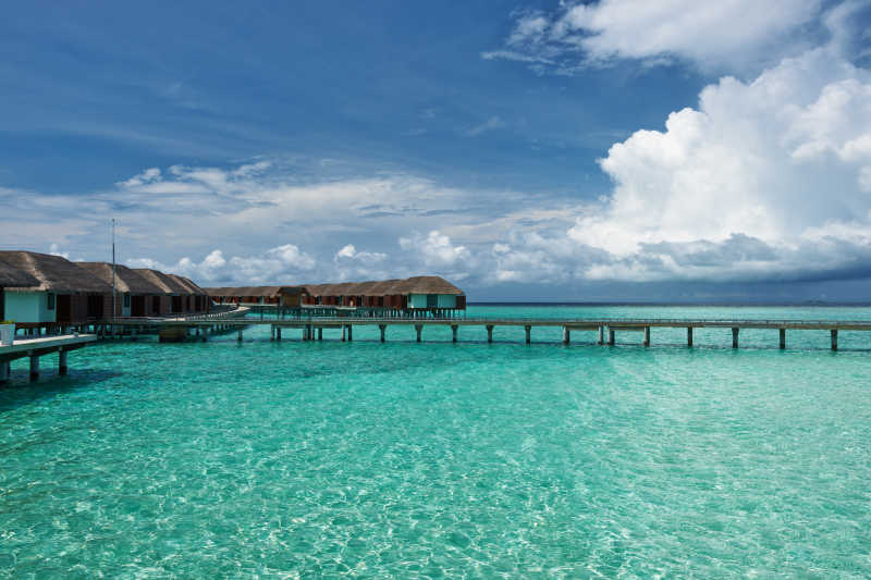 蓝天白云下清澈蓝绿色海面上的度假屋