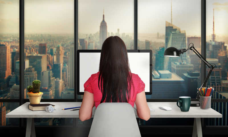 在电脑前工作的长发女性背影