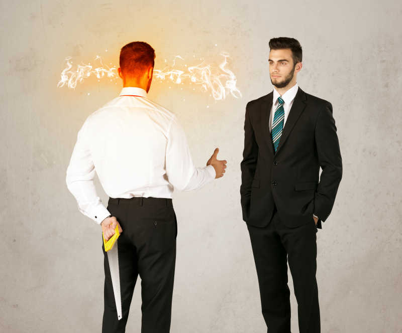 愤怒的商人背后藏着一件武器和别人握手