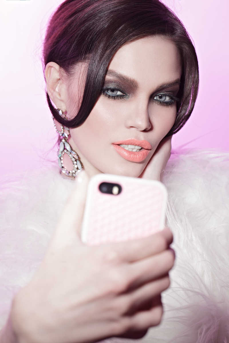 粉色背景前自拍的烟熏妆女孩