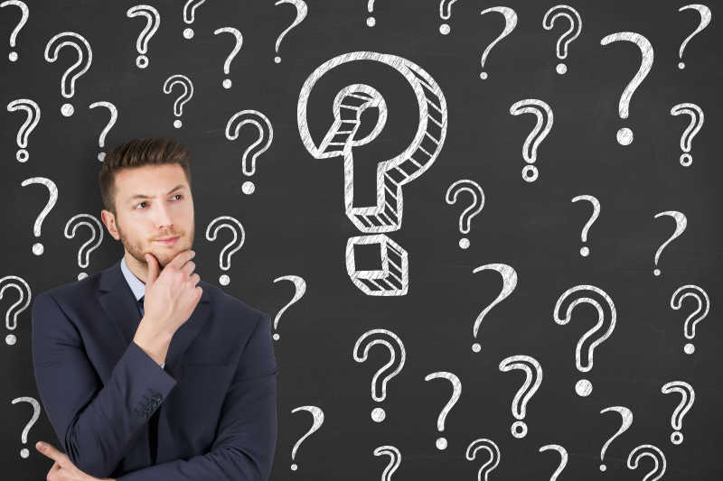 商人站在画满问号的黑板前