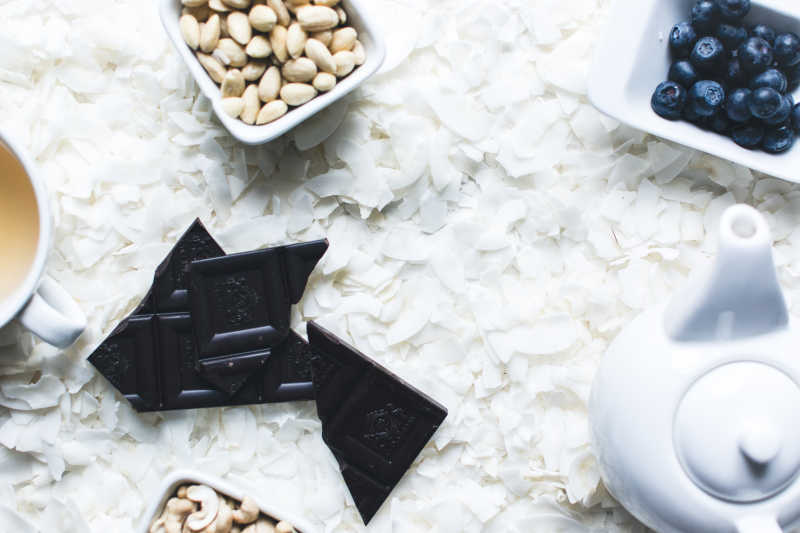 散落的白色椰蓉上的茶水巧克力和腰果蓝莓等