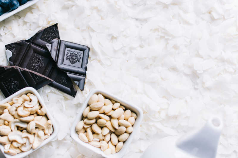 散落白色食材上的碗装腰果和巧克力
