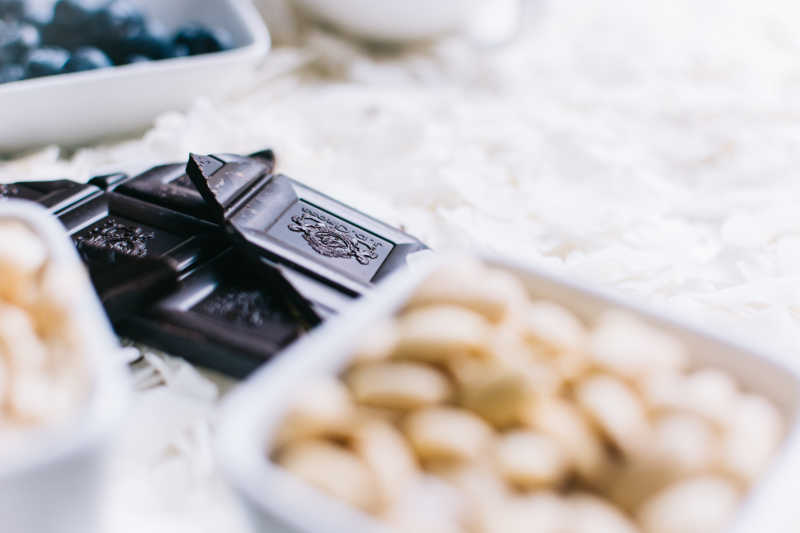 散落的白色椰蓉上的碗装腰果和巧克力