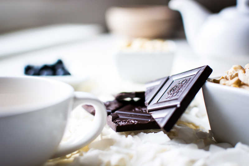 白色椰蓉上的碗装腰果巧克力和茶杯