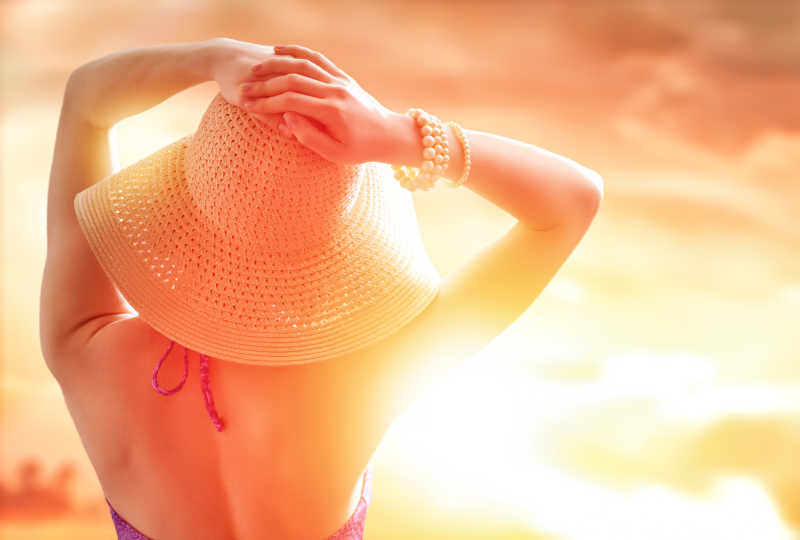 夏日阳光下戴草帽的女子背影
