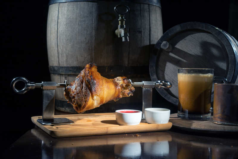 啤酒桶和烧烤叉上的完整猪腿