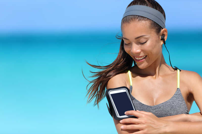 在海边带着手机耳机的女人
