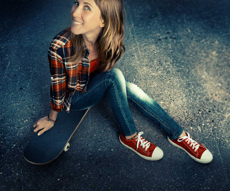 坐在黑色滑板上的女孩