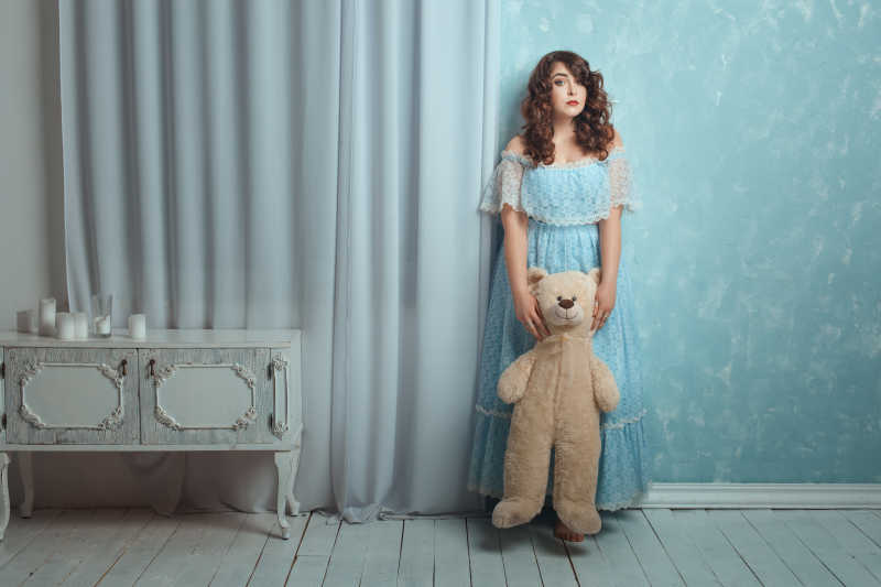 化妆台边抱着熊站着的美女