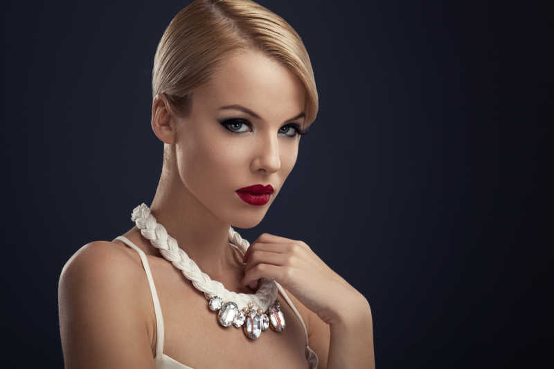 黑色背景下的带项链的红唇女人