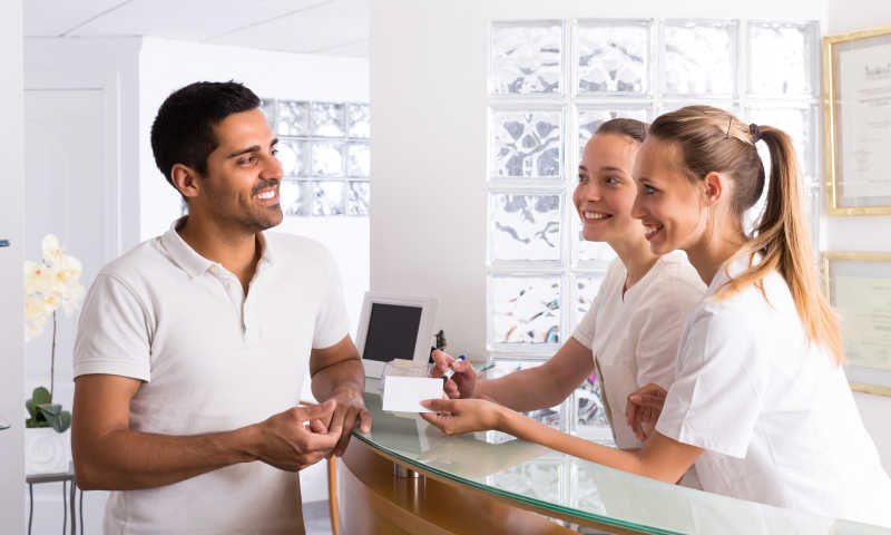 微笑的男人在接待处与两个护士交谈