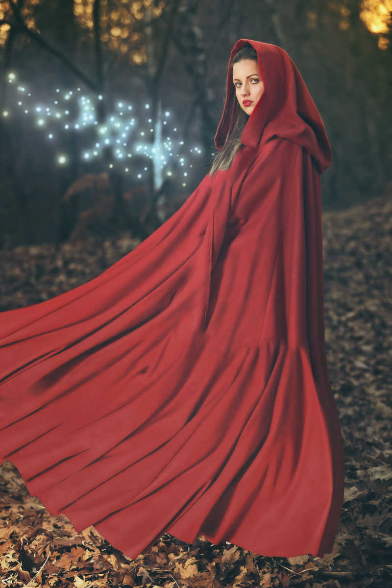 在树林中披着红色斗篷的漂亮女人