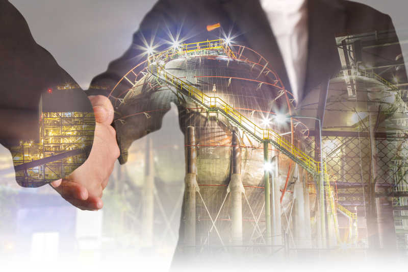 灰色炼油厂背景下的握手